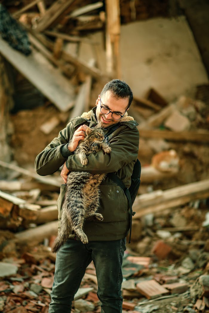 Man warmly embraces his cat amidst a backdrop of urban ruins, depicting resilience.